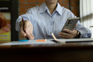 Fototapeta premium the businessman is sitting at a desk with a calculator and a stack of papers. She is looking at the papers and seems to be deep in thought 