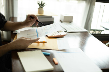 the businessman is sitting at a desk with a calculator and a stack of papers. She is looking at the...