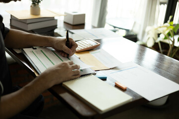 the businessman is sitting at a desk with a calculator and a stack of papers. She is looking at the...