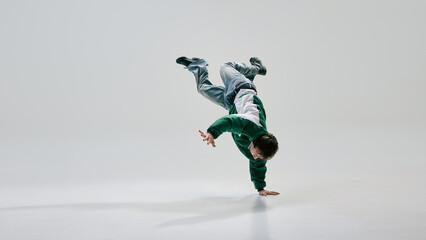 Urban artist, dressed retro attire, spinning into gravity-defying pose with body suspended in...