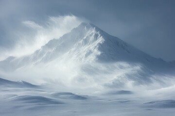 Snowy mountain peak in winter landscape. Wind and snow blowing around summit. Cold weather scene. White and blue tones. Frozen ground with drifts.