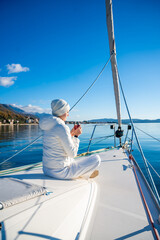 Obraz premium Woman hands holding thermo mug sitting on bow of the yacht during sailing in the morning in winter time in Adriatic sea, relaxation in yachting time