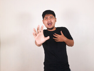 Naklejka premium Handsome Asian man wearing a black shirt with a gesture of pain in his chest due to a heart attack and lung problems. Gesture asking for help