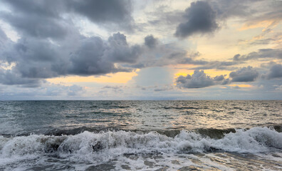 Stormy sea waves under a cloudy sky at sunset