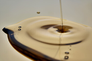 Texture of pouring cosmetic oil on a golden background.