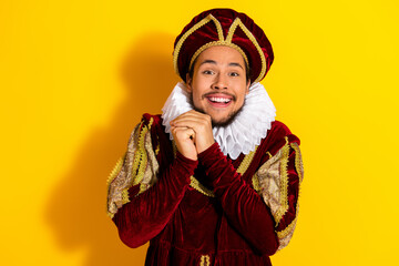Cheerful man dressed as a royal aristocrat in vintage costume on a vivid yellow background