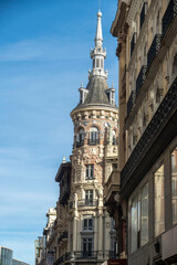 Fototapeta premium A tall building with a steeple is surrounded by other buildings