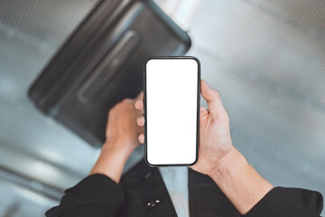 Top view of man using smartphone with white blank screen mockup in airport terminal, Traveler with phone with suitcase, copy space for advertising.