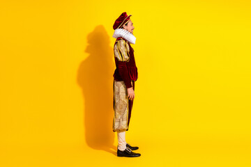 Fototapeta premium Portrait of a man wearing a baroque costume and posing against a vibrant yellow background
