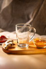Empty transparent cup on wooden tray with turmeric and chili species. Mock up for design. Served table. Preparation for making drink