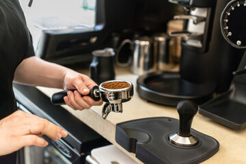 Unrecognizable barista holding a portafilter with freshly ground coffee, ready for tamping