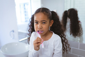 Young girl brushing teeth in bathroom, focusing on dental hygiene routine, copy space