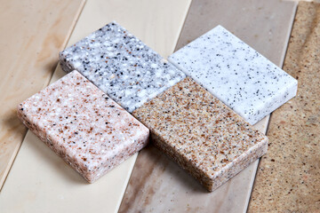 Porcelain stoneware artificial stone square samples as kitchen countertop examples of future kitchen fasade exterior. Samples slabs of natural granite marble quartz for stone countertops close up.