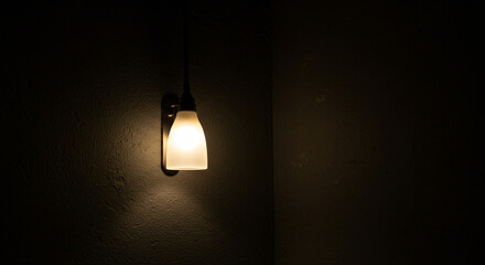 Single Lit Lantern Hanging On Textured Dark Wall In Corner Illuminating Interior Space