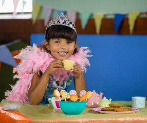 Young girl in princess costume enjoying tea party with colorful treats, copy space