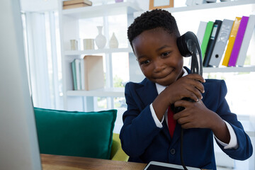 Young boy in suit using vintage phone in modern office, smiling confidently, copy space