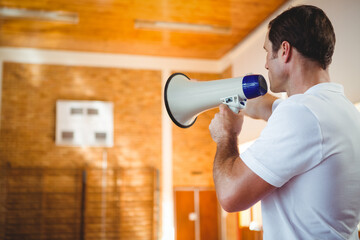 Coach using megaphone in school gym, motivating basketball team during practice, copy space