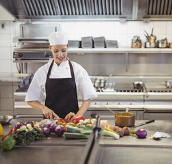 In professional kitchen, chef chopping vegetables, preparing meal with focus, copy space