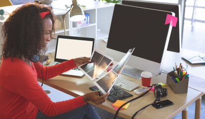Creative professional reviewing design prints at modern office desk with technology, copy space