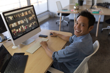 Smiling man participating in video conference at modern office desk