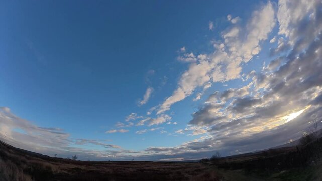 Fish-eye time-lapse footage of the clouds moving in the blue sky over a grassland in Derbyshire, UK