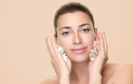 Woman applying ice cubes to her face for beauty and skincare routine against a white background