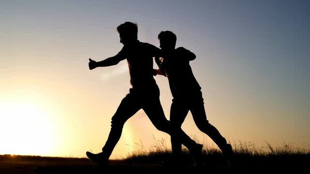Silhouette of two friends playing and running on the field Friendship Day concept