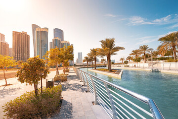 Palm trees and modern architecture reflecting in the water of a canal in a city park of Al Reem, Abu Dhabi