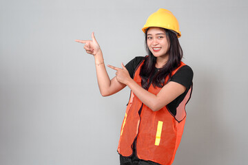 Smiling Asian female construction worker wearing a yellow hard hat and orange safety vest...