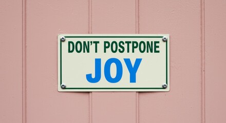 Obraz premium A rectangular off-white sign with rounded corners displaying 'DONT POSTPONE JOY'