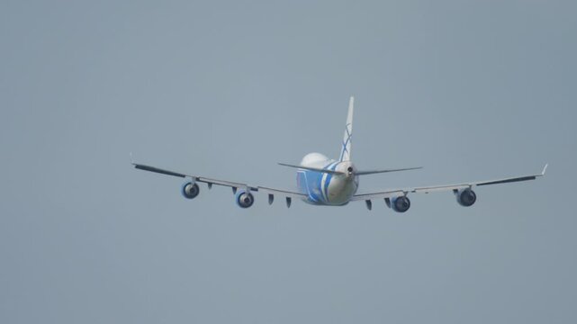Heavy four-engine cargo aircraft climbing after takeoff. Airliner in the sky. Airplane flying away