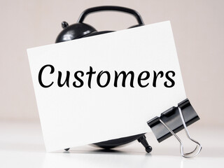 customers text meaning on white note paper background alarm clock