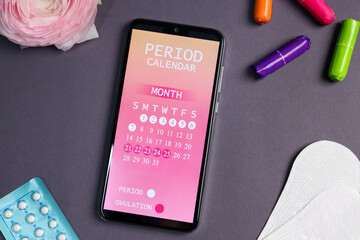 Smartphone with period calendar application, menstrual products and flower on grey background, flat...