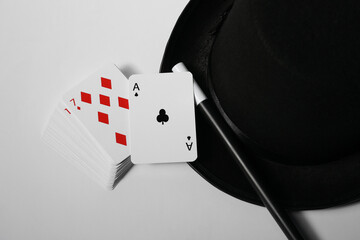 Playing cards, hat and magic wand on light background, closeup