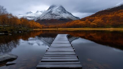 Obraz premium Tranquil mountain lake in autumn. Wooden pier leads to misty peaks