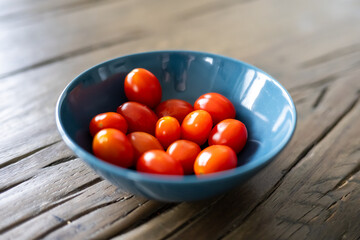 A blue bowl filled with red tomatoes