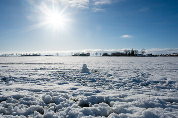 A snow covered field with a snowman in the middle