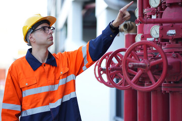 Male engineer inspects water pipelines in the engineering system area of the factory outside where various pipelines are designed modernly. Technicians work in the industry.