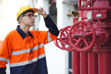 Male engineer inspects water pipelines in the engineering system area of the factory outside where...