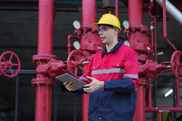 Male engineer inspects water pipelines in the engineering system area of the factory outside where various pipelines are designed modernly. Technicians work in the industry.