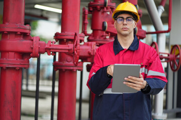 Male engineer inspects water pipelines in the engineering system area of the factory outside where various pipelines are designed modernly. Technicians work in the industry.