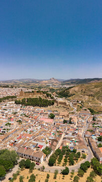 Vertical aerial view of Antequera City. View of Antequera's castle with "Pe&ntilde;a de los Enamorados" mountain in background. Clear blue sky. Famous travel destination in Spain, Andalucia.