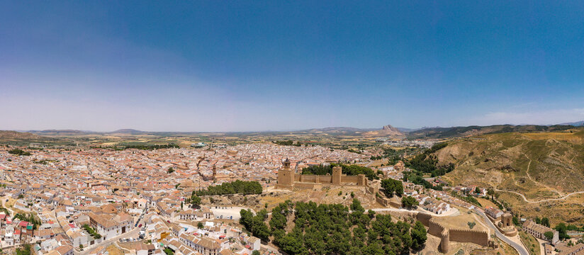 Panoramic aerial view of Antequera City. View of Antequera's castle with "Pe&ntilde;a de los Enamorados" mountain in background. Clear blue sky. Famous travel destination in Spain, Andalucia.