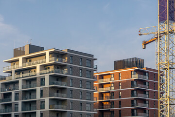 crane lifting construction elements against the background of urban building facades. modern construction of residential properties for rent and ownership on the estate.