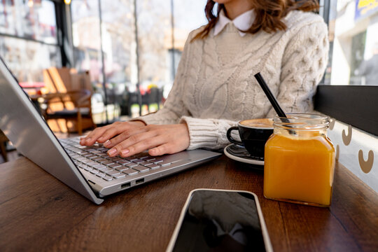 Freelancer woman working on laptop in cafe, drinking orange juice and coffee