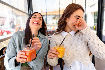 Two friends laughing and drinking smoothies at a bar