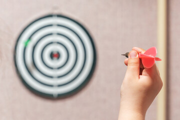 Playing darts, child's hand aiming a dart at a target