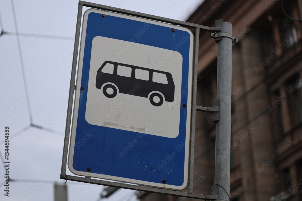 Poster street sign featuring a blue and white design with a bus passing by.