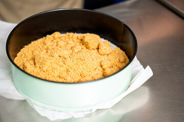 Pastry chef preparing crumble base for dessert in round baking pan