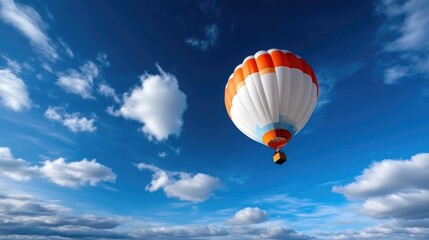 Naklejka premium Colorful hot air balloon soaring through a vibrant blue sky dotted with fluffy white clouds